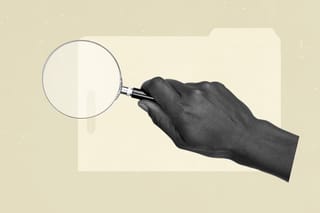 Hand holding a magnifying glass over a folder