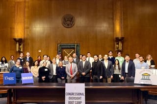 Wide shot portrait of boot camp attendees behind a sign reading "Congressional Oversight Boot Camp."