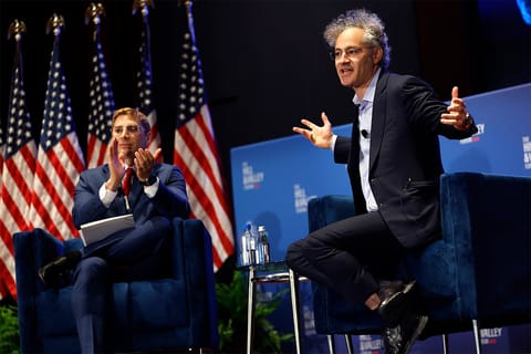 Alex Karp, sitting next to Jacob Helberg, speaks on a stage with a "The Hill & Valley Forum" logo backdrop.