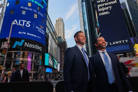 Eric Trump and his brother Donald Trump Jr. smiling while standing outside of NASDAQ in Times Square.