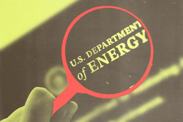 A hand holds a magnifying glass over the U.S. Department of Energy logo