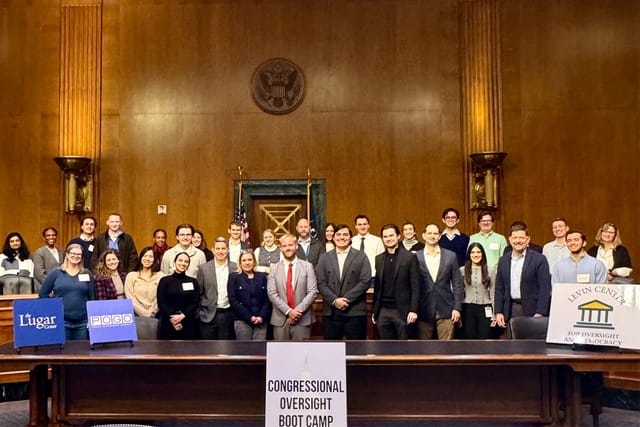 Wide shot portrait of boot camp attendees behind a sign reading "Congressional Oversight Boot Camp."