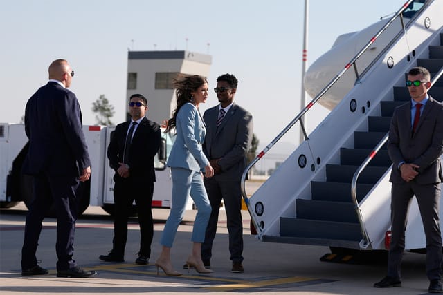 Former DHS Secretary Kristi Noem walks towards boarding stairs to a plane.