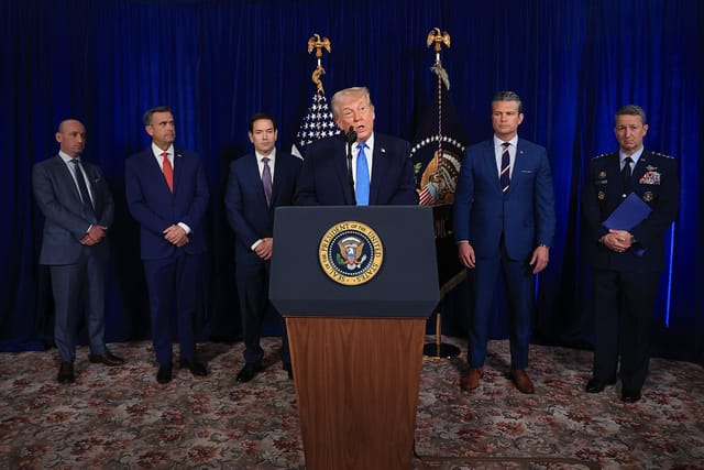 U.S. President Donald Trump speaks at a podium. White House Deputy Chief of Staff and Homeland Security Advisor Stephen Miller, CIA Director John Ratcliffe, U.S. Secretary of State Marco Rubio, U.S. Secretary of War Pete Hegseth and Chairman of the Joint Chiefs of Staff Dan Caine stand in the background.