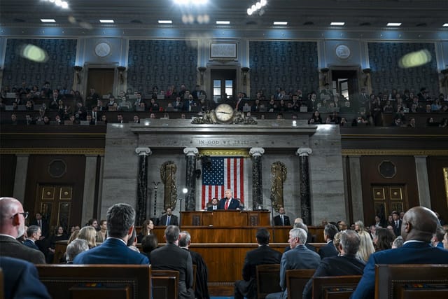 U.S. President Donald Trump, center, speaks at the podium in the House of Representatives chamber. Behind him, U.S. Vice President JD Vance and Speaker of the House Mike Johnson (R-LA) look on.